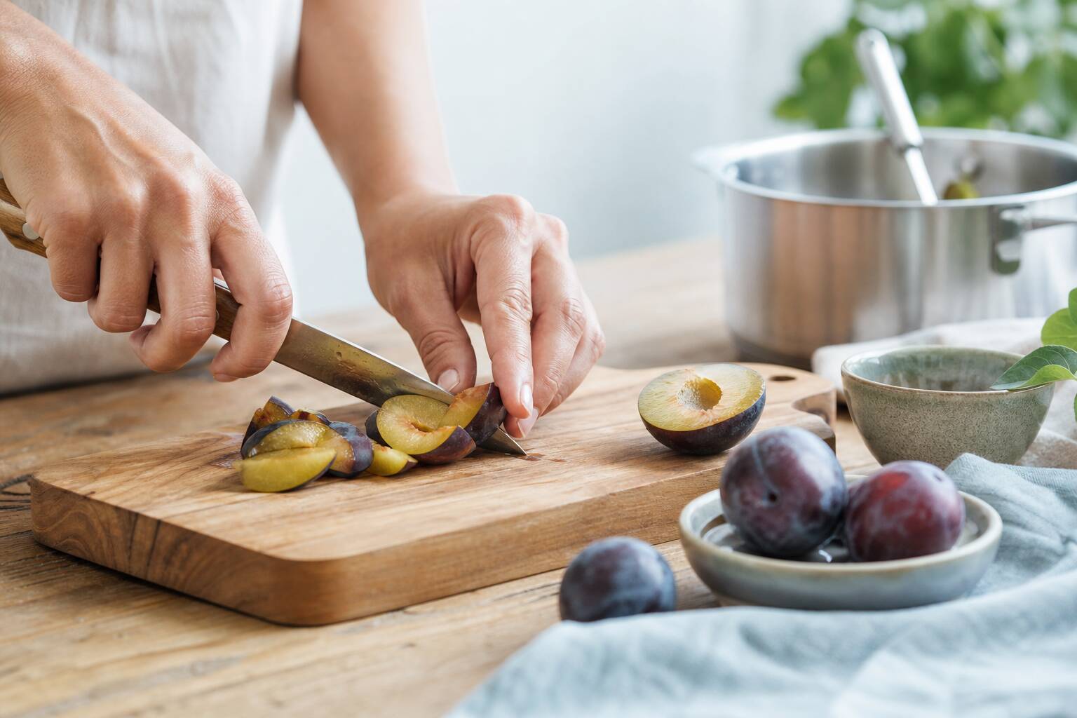 Préparation de la compote de prunes, découpe des fruits sur une planche en bois, recette facile et saine